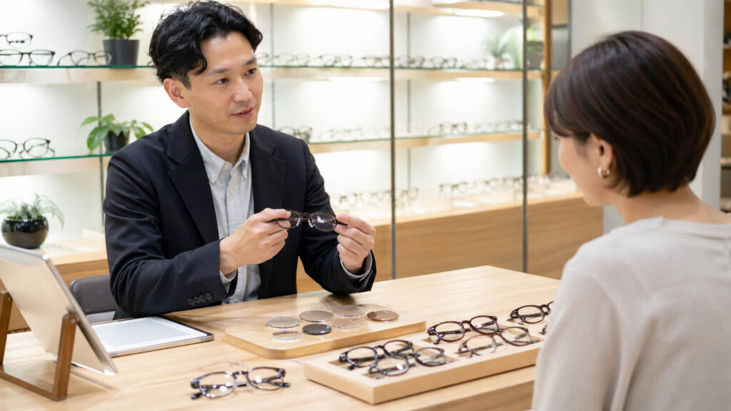 メガネ店で遠近両用メガネフレームとレンズの見積もりを説明している様子