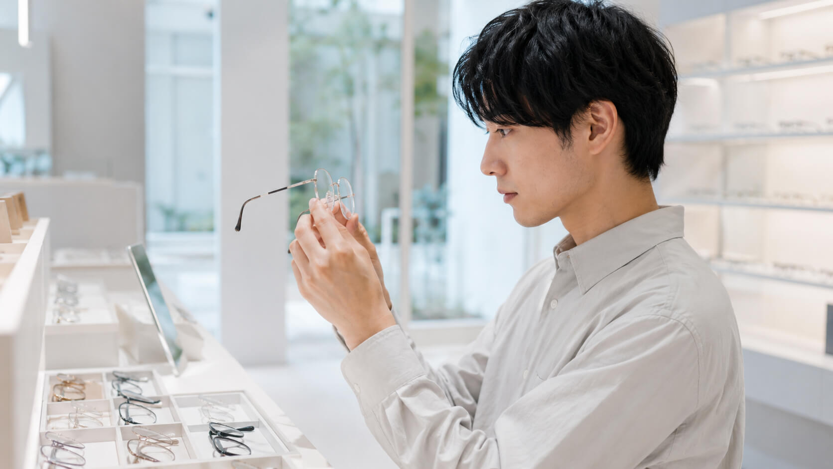 JINS店で、薄型レンズのメガネを手に取って確認している人物